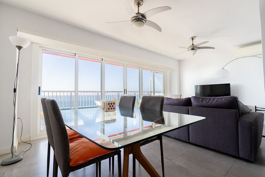 Apartamento Neptuno en Santa Pola: comedor con mesa de cristal frente al ventanal corrido con vistas al mar