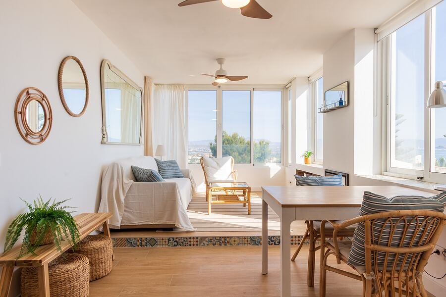 Casa Mar de Pinos en Gran Alacant: salón comedor con espejos redondos, sillas de fibra y ventanal corrido al mar