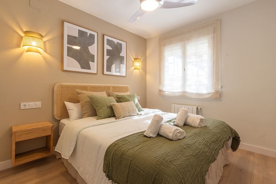 Casa Olivo de Oro en Gran Alacant: dormitorio principal con manta verde oliva, apliques de mimbre y láminas en blanco y negro